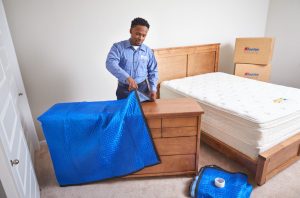 man covering furniture with plastic sheet